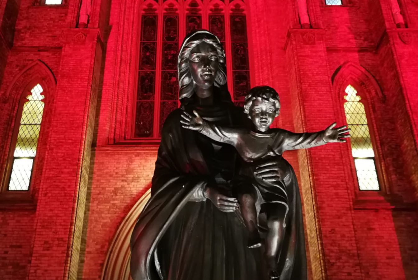 Statue of Mother Mary in front of Cathedral lit in red